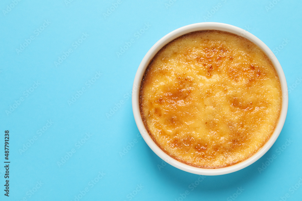 Delicious creme brulee in ceramic ramekin on light blue background, top view. Space for text Delicious creme brulee in ceramic ramekin on light blue background, top view. Space for text