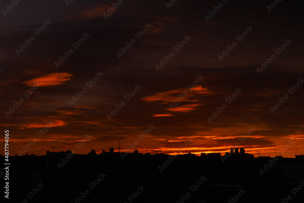 Colorful orange sunrise over city and dramatic sky with clouds - sun goes up, warm illumination. Nature, urban, morning, peaceful, atmospheric view concept