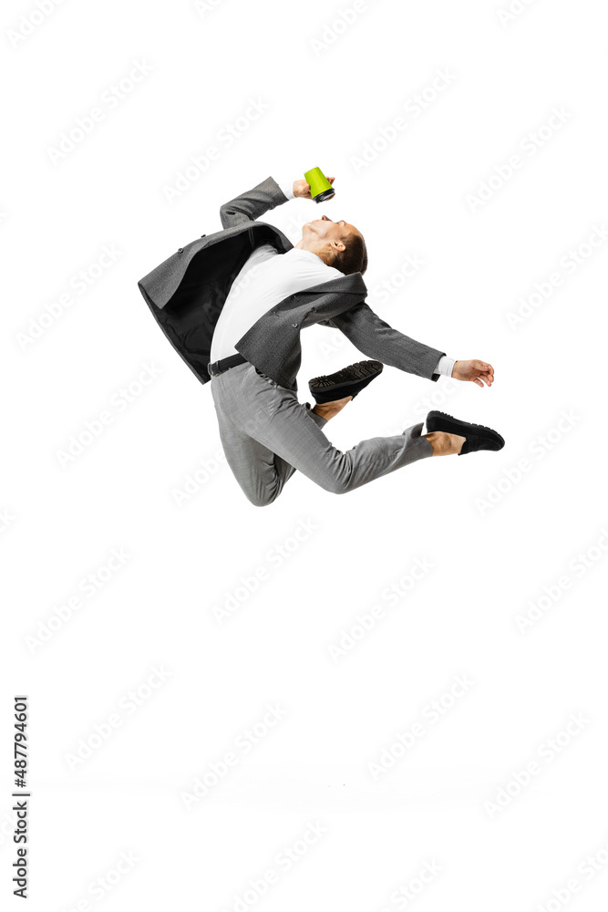 One young man in gray business suit jumping, flying isolated on white background. Business, art, motion, action, creativity, inspiration concept.