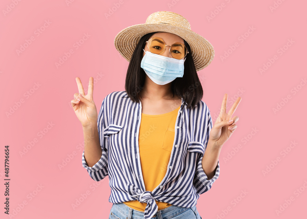 Asian woman in mask showing peace sign Asian woman in mask showing peace sign