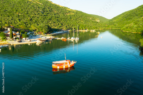 Marina with moored boats near oyster farm in Lim bay. Water flowing into Adriatic sea and surrounded by high mountains covered with forest. Aerial view