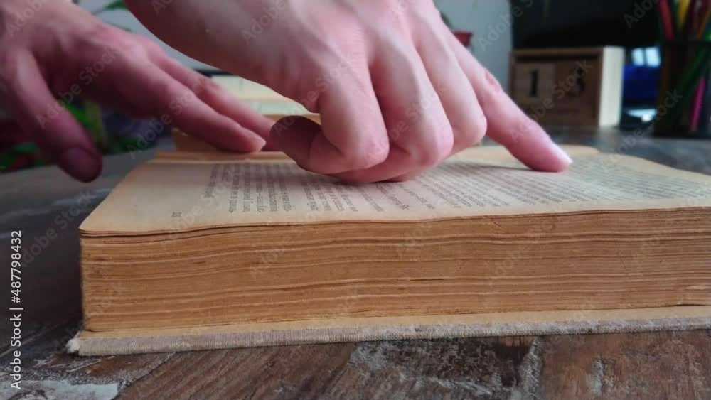 Hand leaves through pages of an old book, soft focus background Hand leaves through pages of an old book, soft focus background