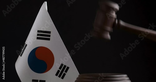 Judge's hammer hits the shock block near the South Korea flag on black background. Wooden mallet next to South Korea flag.