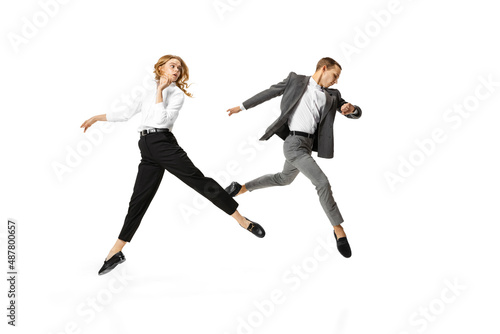 Busy day. Two stylish office workers in business suits in action isolated on white background. Art, beauty, fashion and business concept