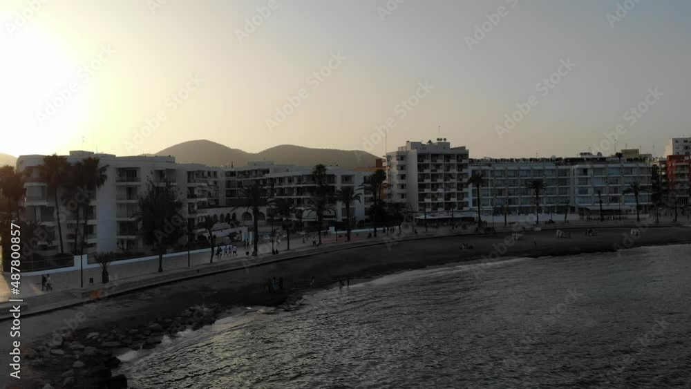 Scenic aerial view of a sunny afternoon on the beach and hotels in Ibiza city with mountains and a sunset in a background in Balearic Island Eivissa in Spain Scenic aerial view of a sunny afternoon on the beach and hotels in Ibiza city with mountains and a sunset in a background in Balearic Island Eivissa in Spain