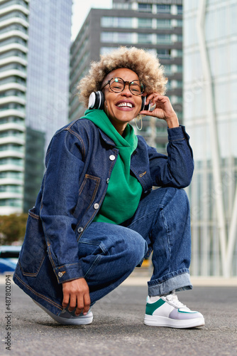 Portrait of young attractive African American girl in urban background hearing music with headphones