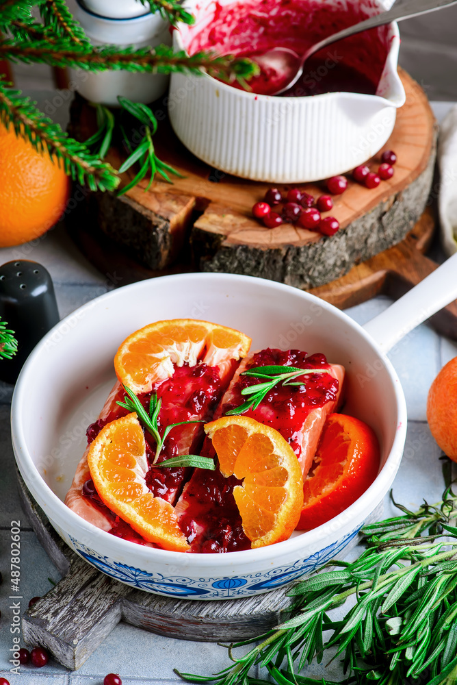 Baked salmon with tangerines in cranberry sauce in a white pan.style vintage