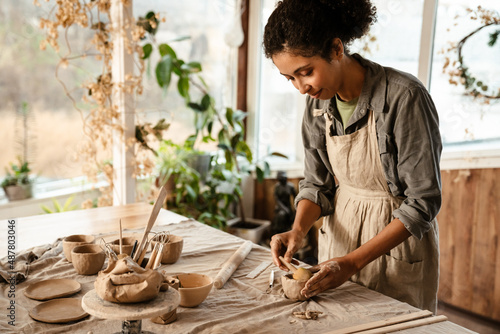 Young black ceramist woman sculpting in clay at her workshop photo