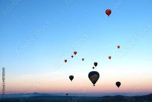 Colourful hot air balloons flying above the mountains, sunrise