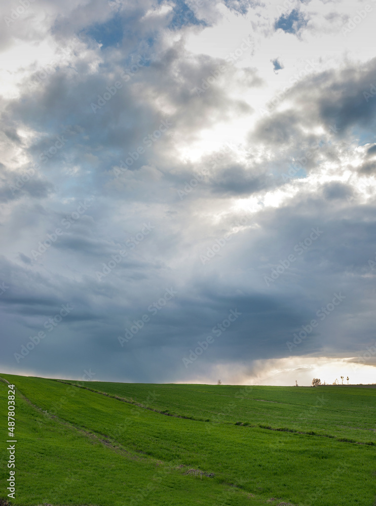 before the storm and beautifully lit green fields in spring. weather, picturesque landscapes before the storm and beautifully lit green fields in spring. weather, picturesque landscapes