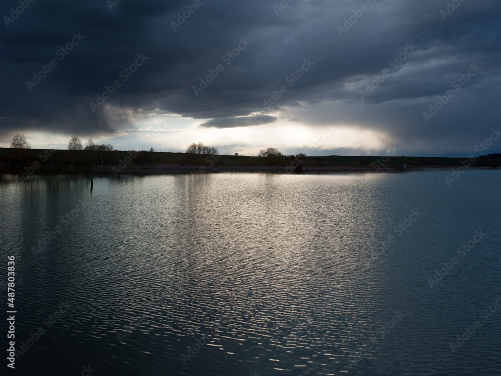 dramatic stormy dark sky over the pond at spring, almost monochrome,siluette