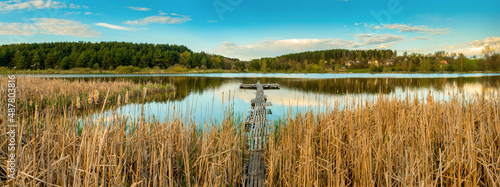 wooden fishing bridge on a cozy rural lake, pier among the reeds, panoramic v...