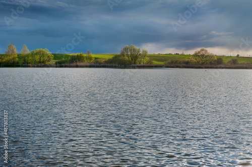 view across the lake to the beautifully lit fields in the spring before the s...