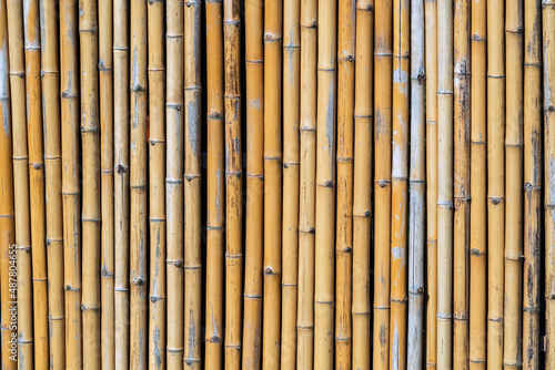 Fototapeta Naklejka Na Ścianę i Meble -  Old brown tone bamboo simple wall or Bamboo fence texture background for interior or exterior design vintage tone. Brown bamboo stick pattern backdrop. Local area urban house protection from thief.