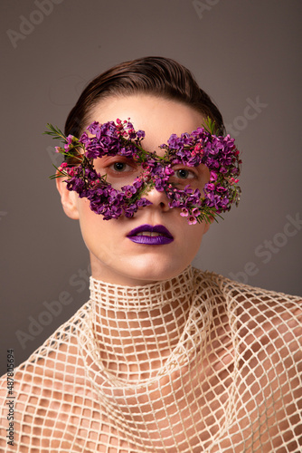 Woman with eye mask made of small flowers portrait isolated on grey brown