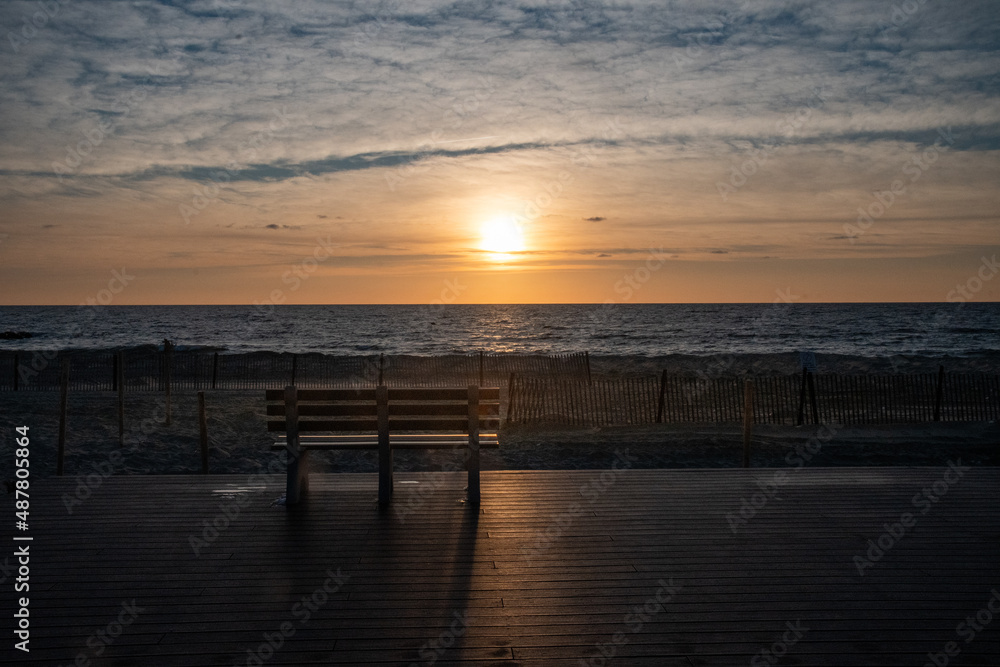 Sunrise and a bench on the boardwalk by the beach