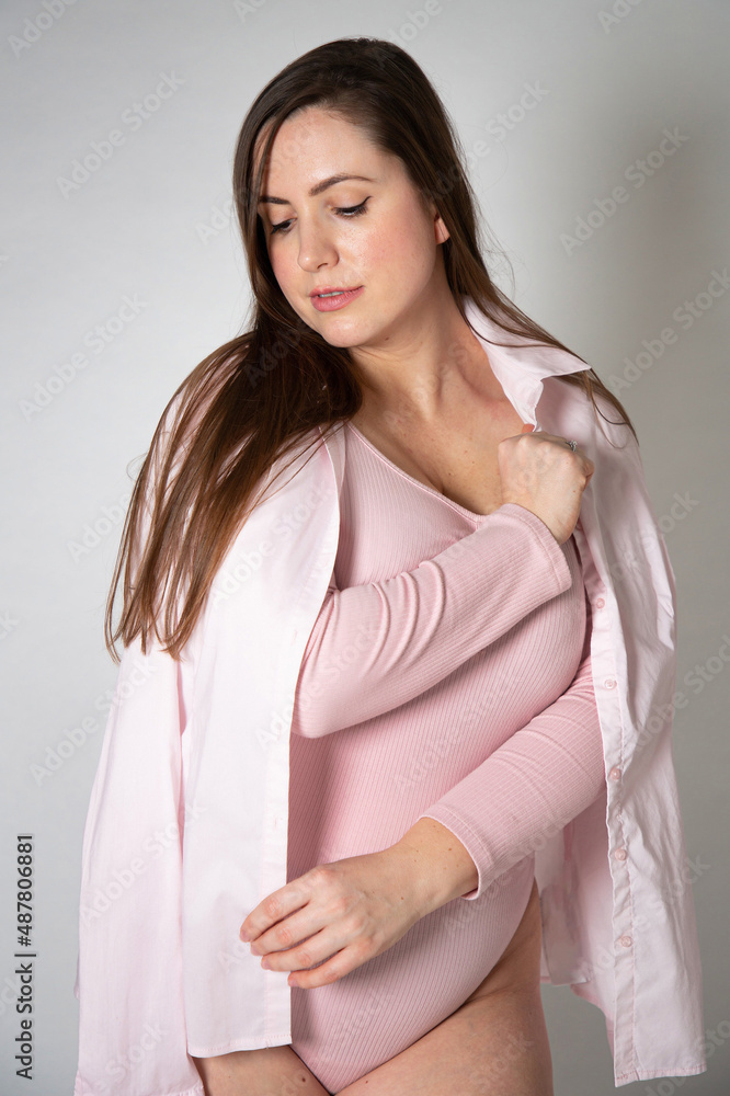 European woman in pastel pink clothes with dark hair standing isolated on grey European woman in pastel pink clothes with dark hair standing isolated on grey