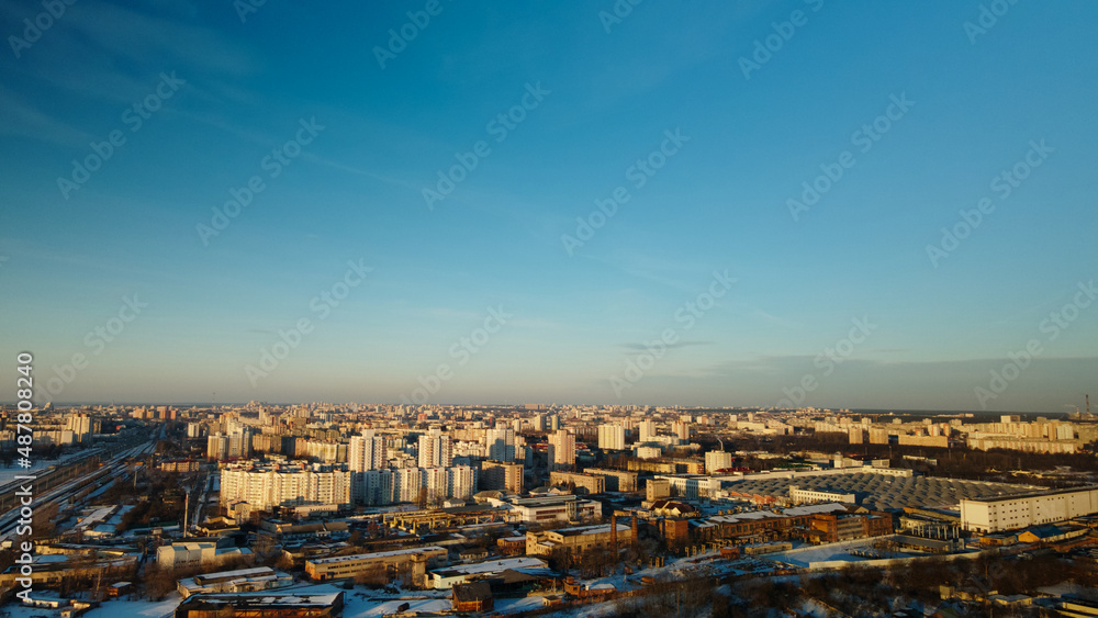 Suburb of a big city. City block from the height of the flight. City highway with busy traffic. Winter cityscape. Golden hour at sunset. Aerial photography.