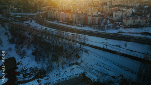 Suburb of a big city. City block from the height of the flight. City highway with busy traffic. Winter cityscape. Golden hour at sunset. Aerial photography.