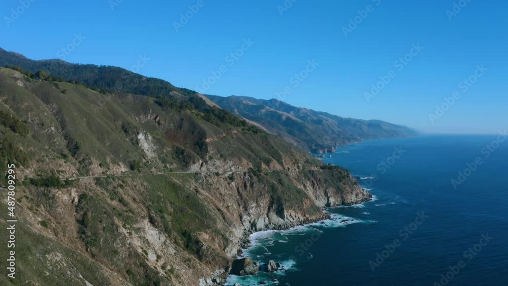 Aerial over the Pacific Ocean with a small highway cutting through the mountainside. Aerial over the Pacific Ocean with a small highway cutting through the mountainside.