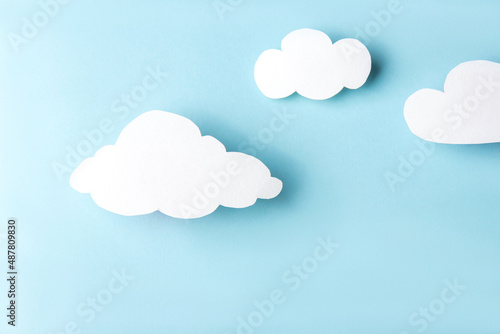 Paper art. White clouds with contrasting shadows on a bright blue background. Flat lay
