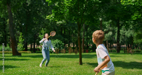 Active boy playing badminton with mother back view. Sport in family life concept