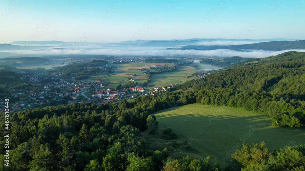 AERIAL: Mist covering the valley in Slovenian countryside clears up at sunrise.