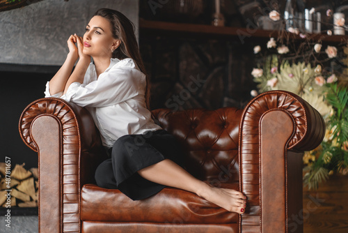 Sad depressed woman at home sitting on sofa looking down and touching forehead, loneliness and pain concept