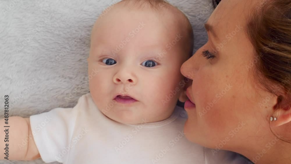 Happy newborn baby with his mother. Healthy newborn baby in a white t-shirt with mom. Closeup Faces of the mother and infant baby. Cute Infant boy and parent, top view. Slow motion. Happy family Happy newborn baby with his mother. Healthy newborn baby in a white t-shirt with mom. Closeup Faces of the mother and infant baby. Cute Infant boy and parent, top view. Slow motion. Happy family