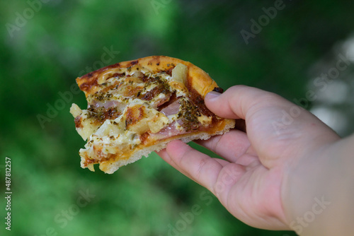 hand holding a pices of pizza 