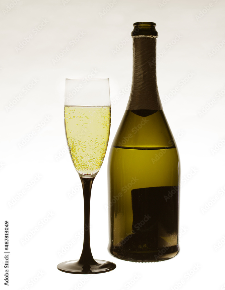 A glass of champagne and a bottle on a light background. A glass of champagne and a bottle on a light background.