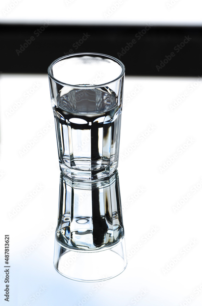 A glass with clean clear water with reflection and sharp shadows