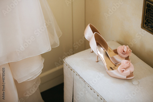 Wedding shoes on table against bridal dress photo