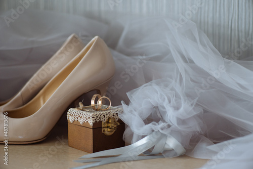 Bridal veil against wedding rings on box and shoes
