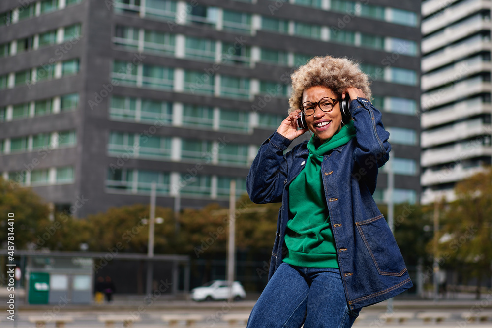 Portrait of young attractive black girl in urban background hearing music with headphones