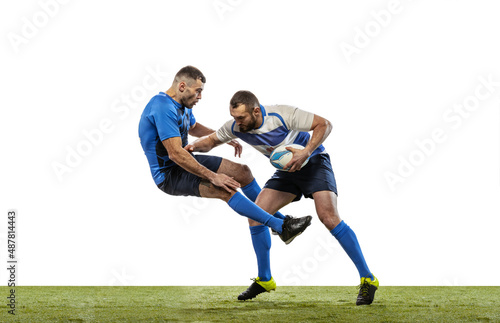 Dynamic portrait of male rugby players playing rugby football on grass field isolated on white background. Sport, activity, health, hobby, occupations concept