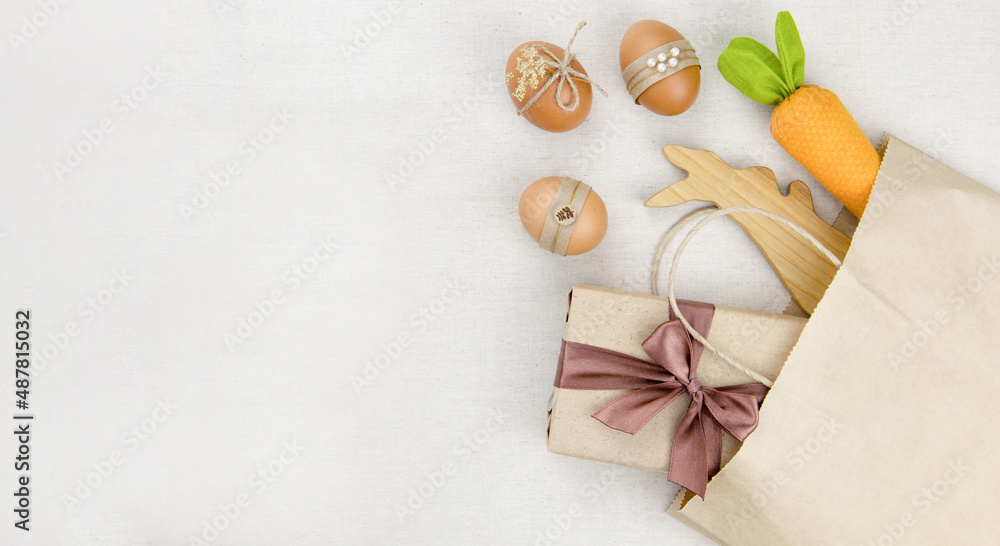 Eggs, carrots and a wooden hare in a kraft bag.on a light wide background.Minimalistic decor for Easter. Spring Religious holiday.The concept of a holiday and shopping for Easter. Eggs, carrots and a wooden hare in a kraft bag.on a light wide background.Minimalistic decor for Easter. Spring Religious holiday.The concept of a holiday and shopping for Easter.