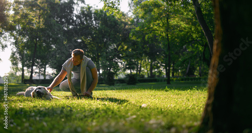 Relaxed man petting golden retriever. Playful dog chew leash lying on grass