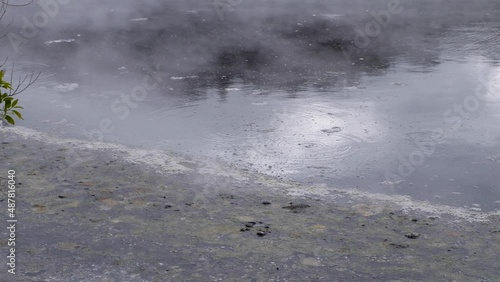 Moody hot pool swamp with bubbles and mist steam drifting over the lake surface. Geothermal hot water environment. Static handheld. photo