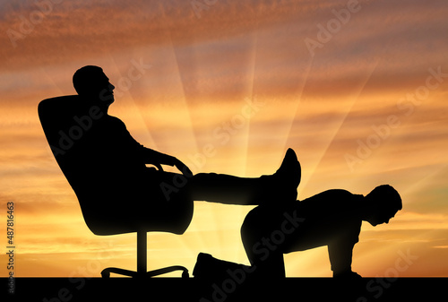 Silhouette of a selfish man sitting in a chair, threw back his legs on the back of a man photo