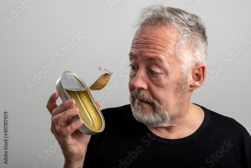 man looking at an empty sardine can