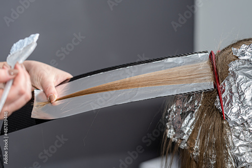 Hair stylist makes bouffant on thin strands and applies bleaching powder using shatush technique. photo