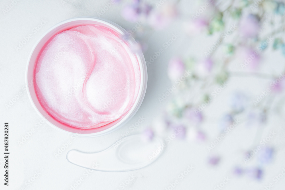 Eye patches. A jar of Hydrogel Hydrating and Rejuvenating Eye Patches. Mask for removing puffiness under the eyes. Pastel colors, blurred flowers on the background Eye patches. A jar of Hydrogel Hydrating and Rejuvenating Eye Patches. Mask for removing puffiness under the eyes. Pastel colors, blurred flowers on the background