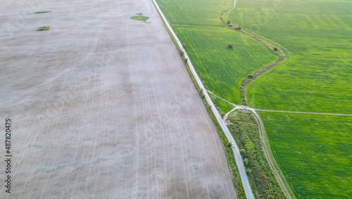 Overhead view of a plowed field next to the highway and a juicy green field