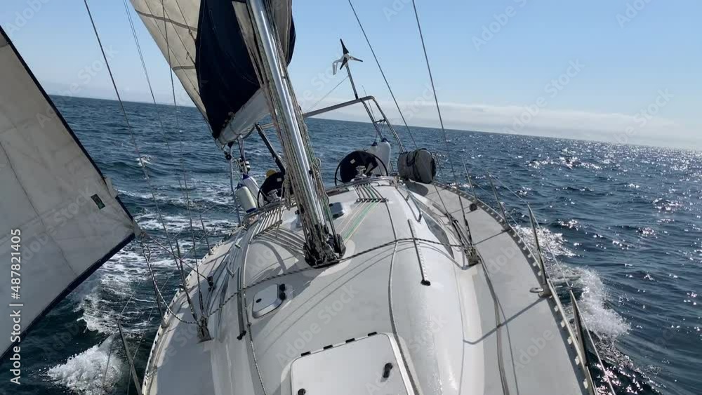 Beautiful sail boat sailing on the sea. The camera is at the bow of the yacht looking backwards (aft) as the boat glides over the waves. Beautiful sail boat sailing on the sea. The camera is at the bow of the yacht looking backwards (aft) as the boat glides over the waves.