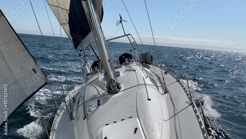Beautiful sail boat sailing on the sea. The camera is at the bow of the yacht looking backwards (aft) as the boat glides over the waves.