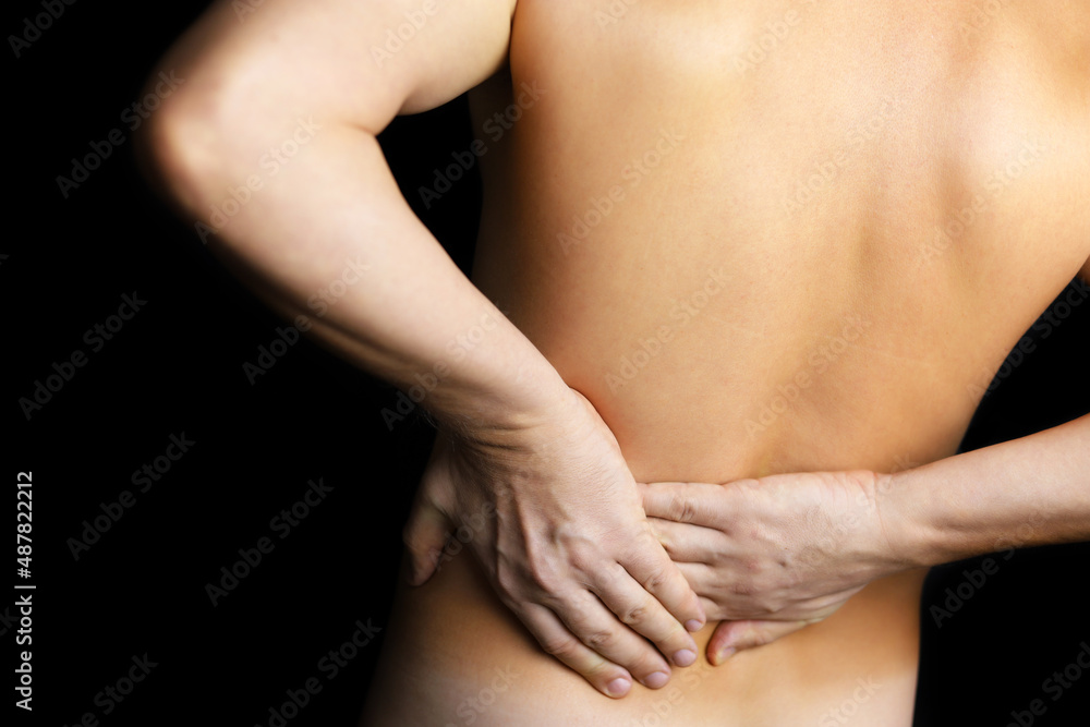 Man with side pain on black background. Shirtless person suffering from backache, diseases of the spine and lower back