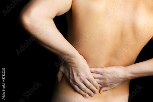 Man with side pain on black background. Shirtless person suffering from backache  diseases of the spine and lower back