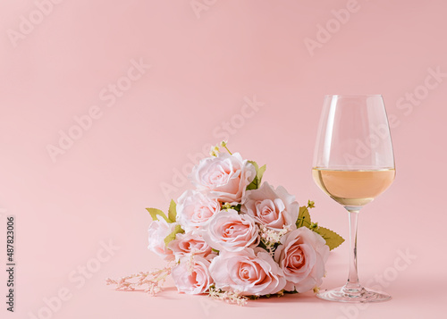 Fototapeta Naklejka Na Ścianę i Meble -  Bouquet of delicate rose flowers on pink background and glass of white wine.