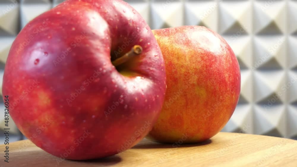 Two Gala apples on a rotating wooden surface, close-up.
Two Gala apples on a rotating wooden surface, close-up.